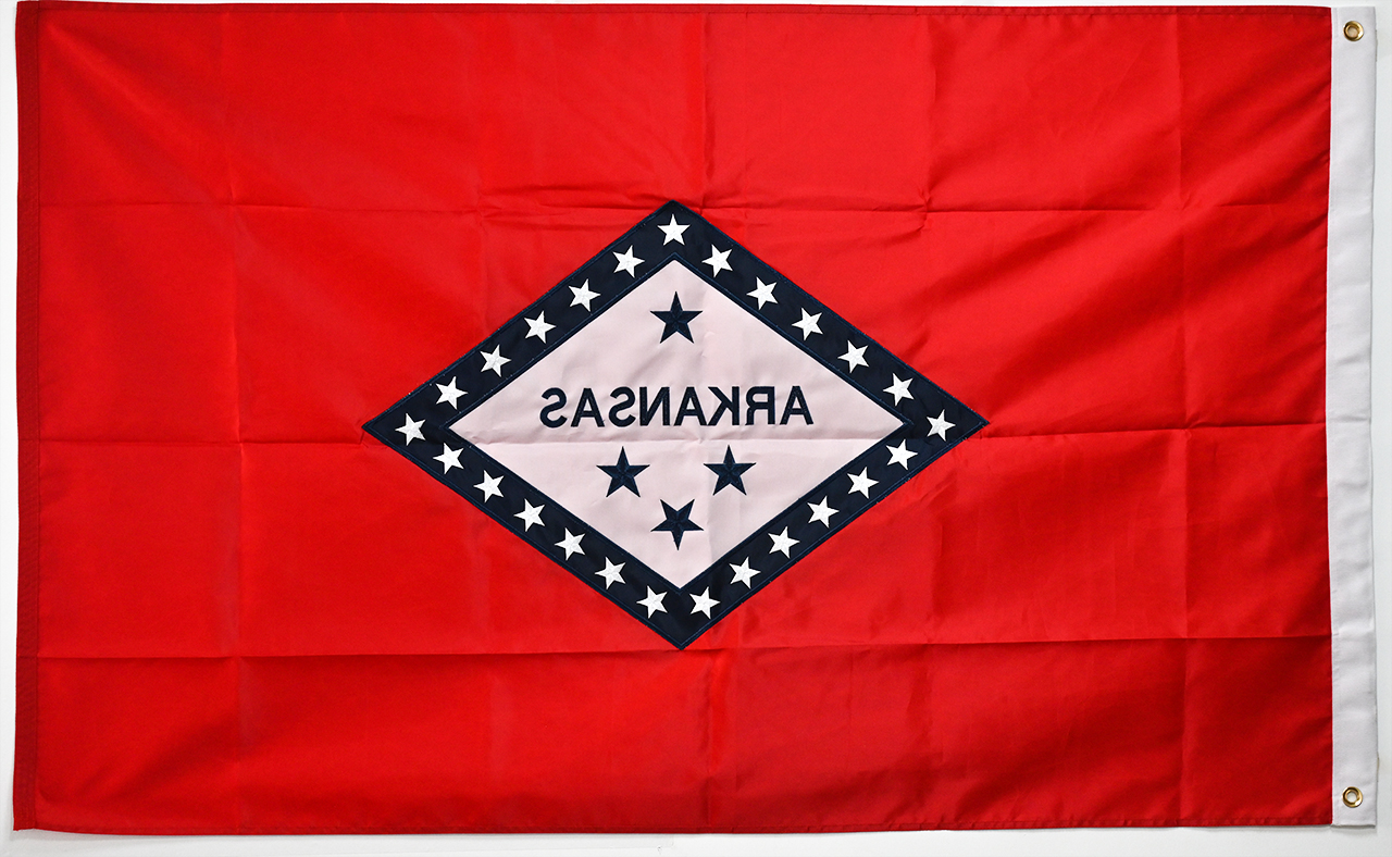 A detailed close-up showing the difference between a screen-printed flag edge, a digitally sublimated pattern, and a sewn-construction flag with reinforced stitching and brass grommets on the header