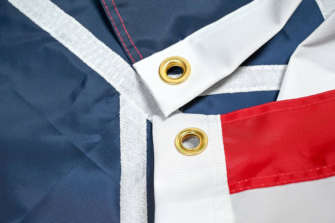 A close-up comparison of 210D polyester and nylon flag fabrics under sunlight, showing texture and color vibrancy.