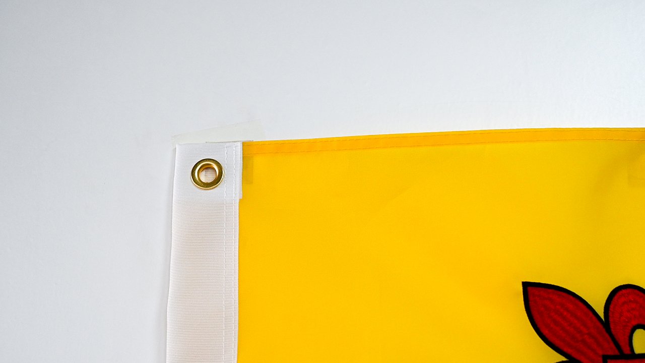 close-up of a flag's reinforced hem, header tape and metal grommets being inspected by hand during quality control