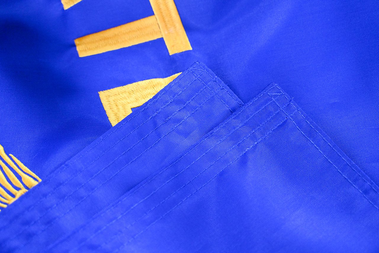 Flag production workshop with rolls of printed fabric, cutting table, and finished flags being packed for shipment