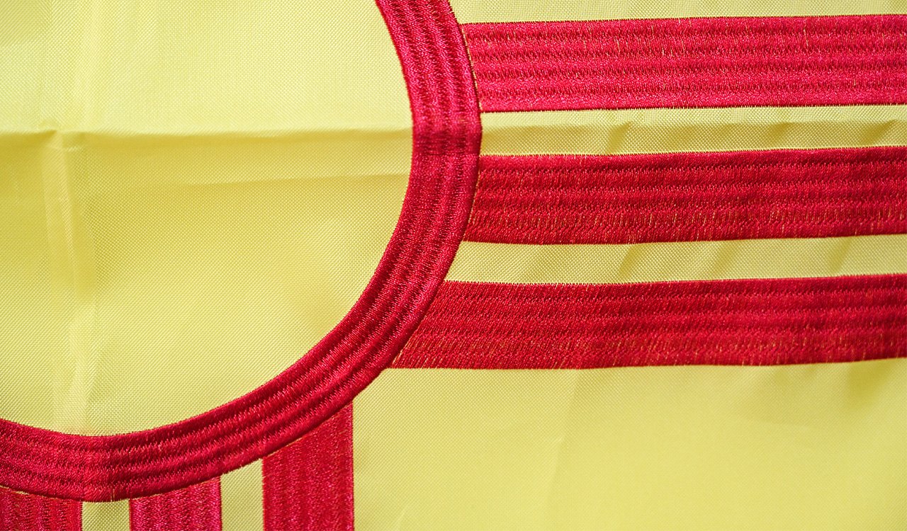 Folded national and custom flags in individual polybags with barcode labels, stacked beside closed export cartons in a packing area