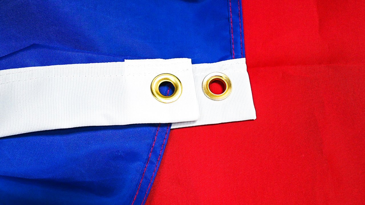 Close-up detail of a national flag emblem showing stars, shield and printed artwork on woven fabric