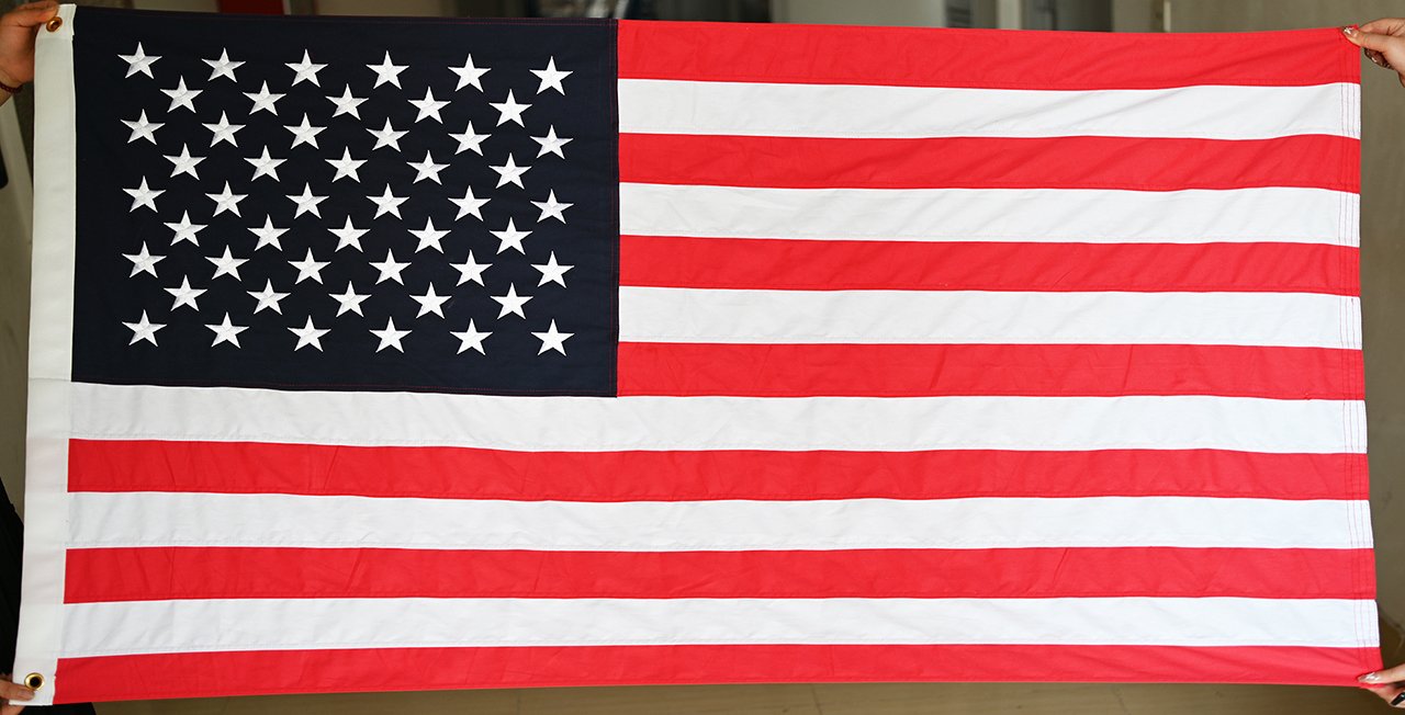 Custom municipal seal artwork on a folded flag beside a printed color proof sheet on a workbench